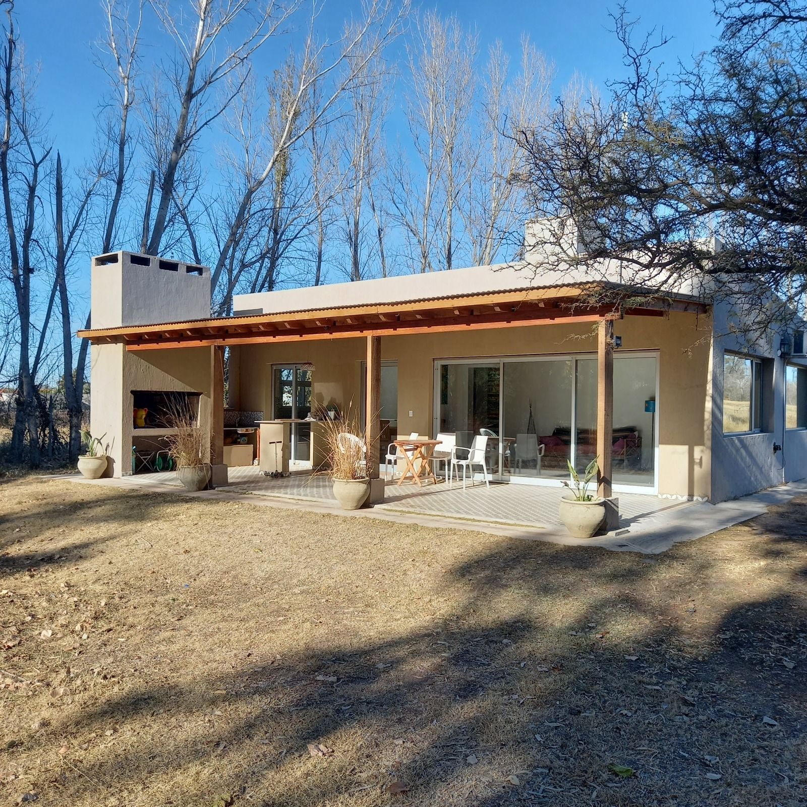 Vivienda de una planta con galería cubierta y estructura de madera, entre árboles