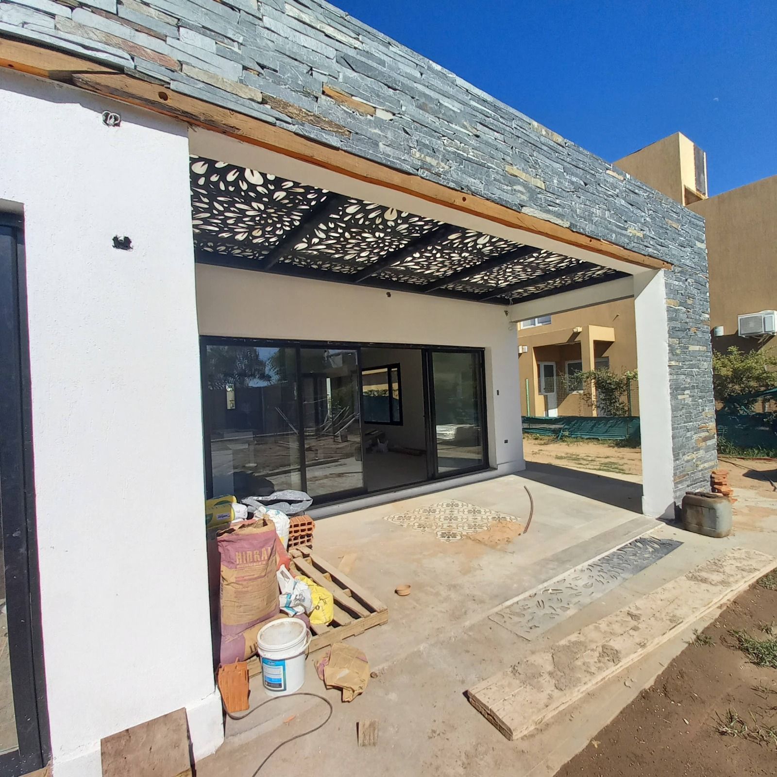 Frente en obra con pérgola de madera calada sobre la galería