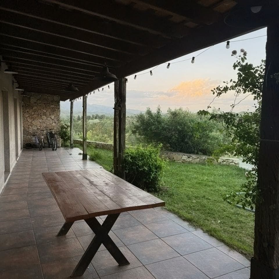 Galería cubierta con mesa de madera maciza y vista al jardín