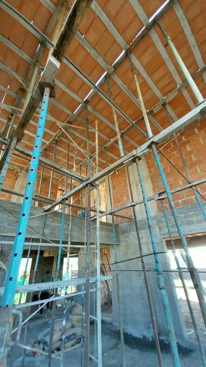 Interior en construcción con puntales metálicos y losa de ladrillo cerámico a la vista